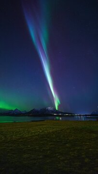 A colorful pillar of light dancing above mountains, fjords and fields of Steigen on March 3rd, 2024.