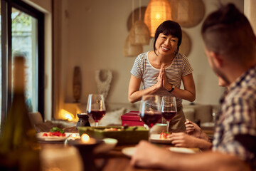 A happy Asian woman feels thankful for her friends' gift, during dinner at home.