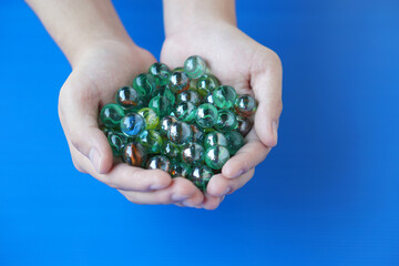 Close up hands holds marbles balls, small spherical object often made from glass, clay, steel,...