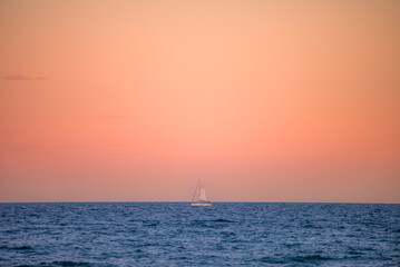 Un bateau à voile seul en mer au coucher de soleil