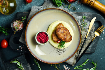 Mashed potatoes with pork chops and beetroot sauce. Homemade food. On a dark stone background.
