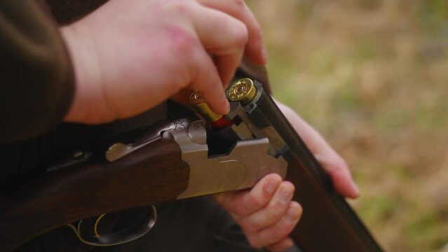 hunter loading shotgut with shells in the forrest close up