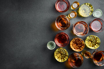 A set of glasses with strong alcoholic drinks: whiskey, brandy, cognac or bourbon and rum. top view. Strong aged alcoholic drinks. On a black stone background.