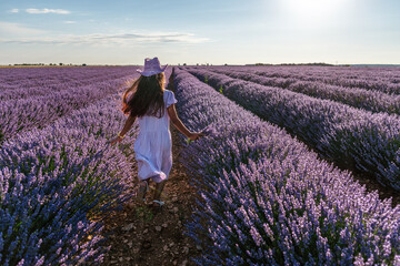 Young girl running between lavender bushes in the  field. Brihuega, Spain.