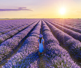 Young girl walking  in the lavender field and stunning sunset sky at the background. Brihuega, Spain.