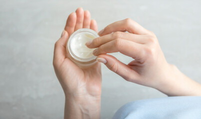 A jar of cream in the hands of a woman, top view. A woman holds hand cream in her hands.