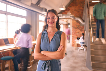 Portrait Of Smiling Young Businesswoman Working In Modern Open Plan Office 