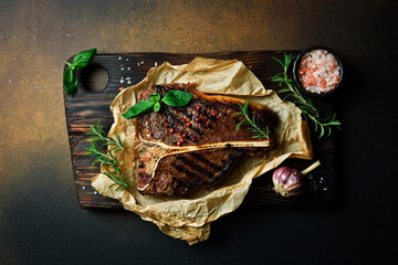 T-bone steak with rosemary on parchment paper. Beef steak on a dark background. Meat.