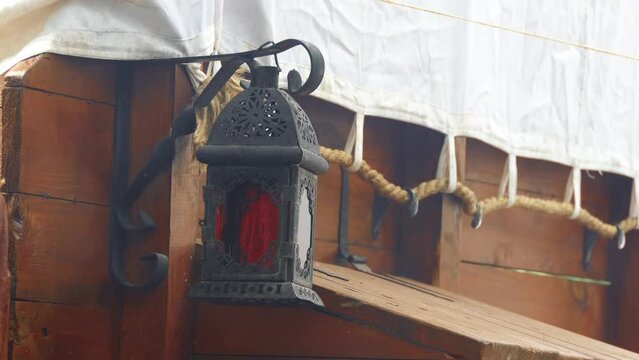 a wooden lantern with a candle sways in the wind at a field camp near the tent