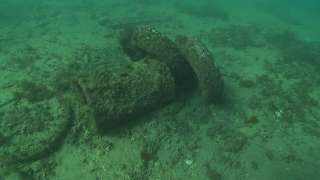 Two tires are placed against a cylinder on the ocean floor, as if they were intentionally stored there Short shot