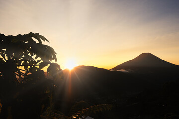 Golden morning sun rays peeping from behind Sindoro mountain, Wonosobo - Indonesia