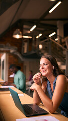 Businesswoman Working In Modern Multi-Cultural Office Listening To Music On Earphones Or Earbuds