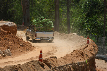 A pickup truck transports a truck full of fresh bananas. road construction is going on. A country road route through a valley along a river where the road is damaged during the rainy season. © CoreRock