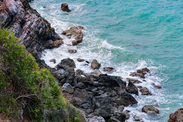 Fototapeta na wymiar high-angle landscape of rocks by the sea The view from the mountain in the island with the cool breeze, green trees and the blue sea. The air is nice and refreshing in the summer in Thailand.