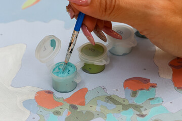 Phukan watercolor in the hands of a middle-aged Asian woman practicing painting in her free time to...