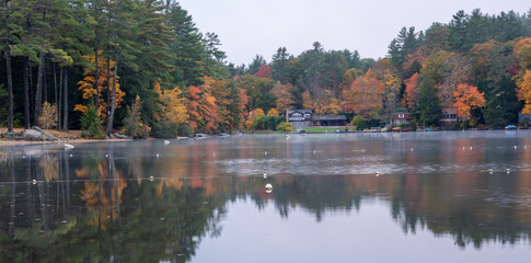 A Calm pond in New England reflects beautiful fall colors