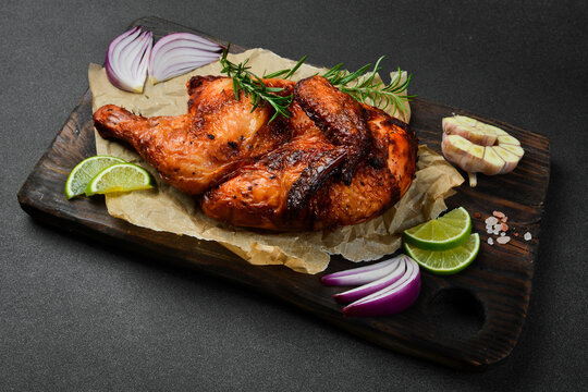 Grilled chicken with rosemary and spices on a wooden board. Traditional festive dish.