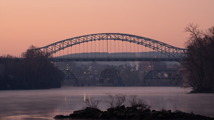 The Arrigoni bridge spans a river with a foggy sky in the background
