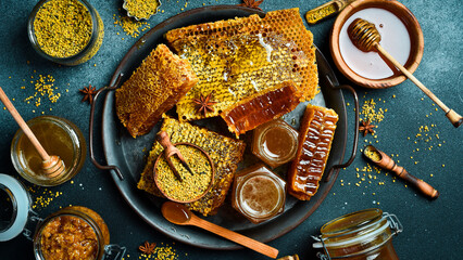 Honey background. Assortment of honey, honeycombs, pollen on a metal tray. On a black stone background