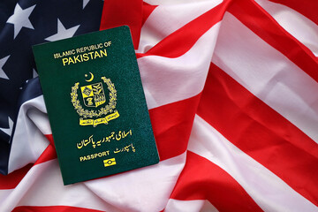 Green Islamic Republic of Pakistan passport on United States national flag background close up. Tourism and diplomacy concept