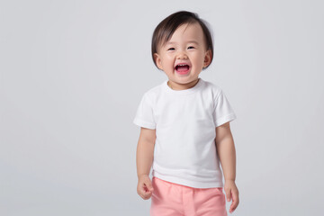 Happy Asian toddler wearing a white t-shirt and pink shirts on a light background
