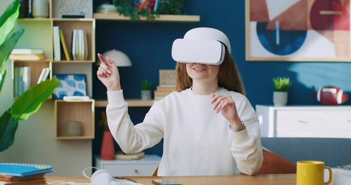 Female using glasses of virtual reality. Modern technic development. Woman gesturing while using 3D virtual glasses. Female exploring vr glasses of virtual reality. Woman sitting at table in office.