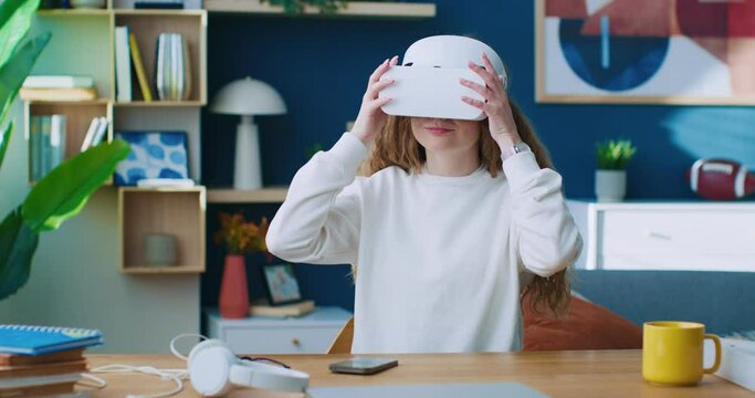 Female using glasses of virtual reality. Modern technic development. Woman taking glasses of virtual reality off. Female talking by phone and sharing emotions. Woman sitting at colorful office.