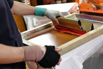 silk screen printing. male hand with a squeegee. serigraphy production. selective focus