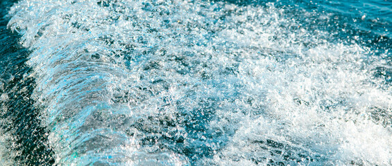 Waves on the sandy beach. Water background, blue sea water. Beautiful texture of sun glare on the water and sea foam.