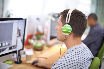 Business, designer and man with headphones at computer screen in office for creative internship and...