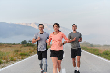 A group of friends, athletes, and joggers embrace the early morning hours as they run through the misty dawn, energized by the rising sun and surrounded by the tranquil beauty of nature