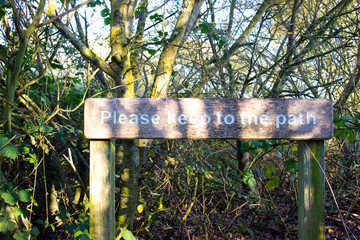 A rustic wooden sign in a woodland saying 