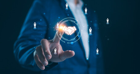 A business professional touches an icon of people connected by lines, centering a handshake symbol,...