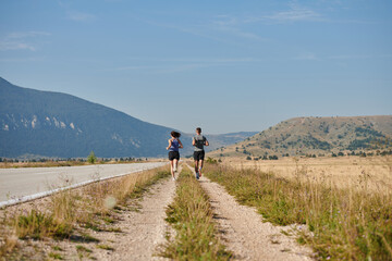 Energized by the beauty of nature, a couple powers through their morning run, their bodies and...