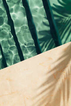 Top view of azure swimming pool water, granite tiles and palm shadow in luxury hotel resort villa. Tropical summer beach background. Poolside architecture natural material inspiration.