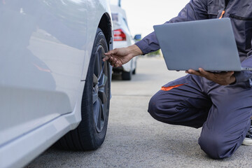 Auto mechanic looks under the hood of a broken car and checks the oil level on the side of the...