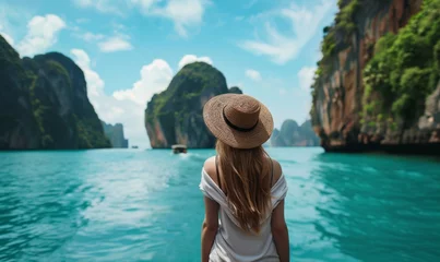 Fototapeten Woman admiring the natural beauty of Phang Nga Bay surrounded by lush greenery and crystal clear water © AlfaSmart