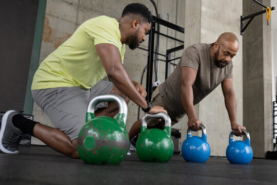 Personal trainer with African American mature male using kettlebells for a workout