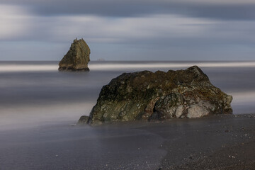 Naklejka premium A rock is on the beach next to the water
