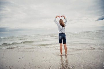 Zwei Mädchen schauen am Strand bei Domburg auf das Meer hinaus und formt mit den Armen ein Herz