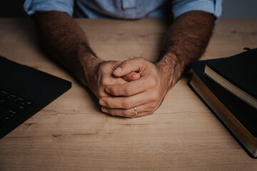 Hand of a man praying, sitting at the table, bible study