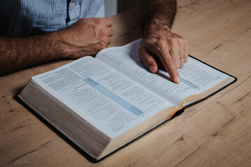 Man is reading the bible pointing with his finger at the text