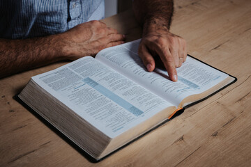 Man is reading the bible pointing with his finger at the text