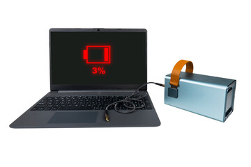 A laptop next to a large power bank (charging station) with a USB cable on a transparent background. On the laptop screen there is a red 3% battery charge indicator (low charge)