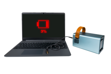 A laptop next to a large power bank (charging station) with a USB cable on a transparent background. On the laptop screen there is a red 3% battery charge indicator (low charge)