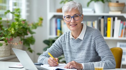 Senior woman writing in notebook in a sunny home office, embodying hopecore trend with a joyful and optimistic atmosphere - obrazy, fototapety, plakaty