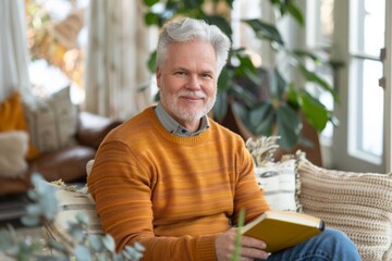 Obraz premium Elderly man with silver hair reading in a sunlit living room, embodying a serene retirement life surrounded by plants and homey comforts
