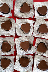 chocolate candies in the shape of a heart in a silver package on a red background. chocolate candies close-up on a red background. red background