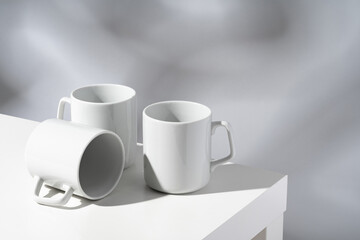 White ceramic mugs on gray background with shadows