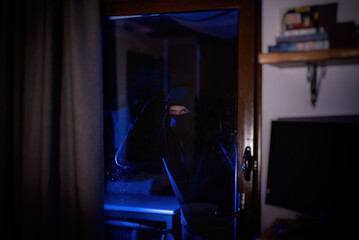 The thief looks through the glass inside the house.